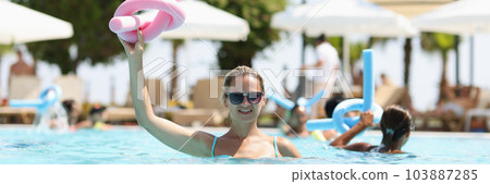 Happy woman holding pink flexible sticks for aerobics 103887285
