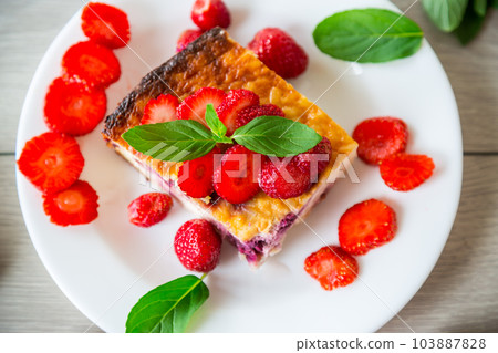 cooked cottage cheese casserole with berry and strawberry filling in a plate 103887828
