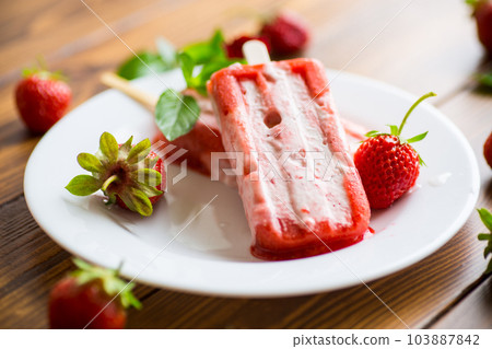 homemade strawberry ice cream on a stick in a plate with strawberries homemade strawberry ice cream on a stick in a plate with strawberries 103887842