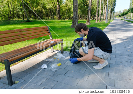 A volunteer removes rubbish in public parks. Pollution of nature, environmental problems. A volunteer removes rubbish in public parks. Pollution of nature, environmental problems. 103888436