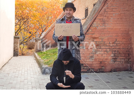 Forgiveness concept. Men holding a sign saying forgive me on a city street 103888449