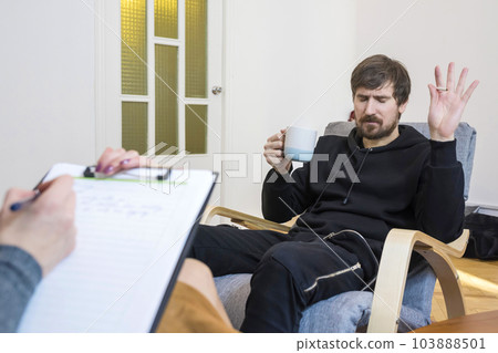 A man at a psychologist, sitting in a chair, talks about his problems. A man at a psychologist, sitting in a chair, talks about his problems. 103888501