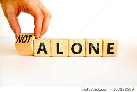 You are not alone symbol. Businessman turns wooden cubes and changes concept words alone to not alone. Beautiful white background. Business, support and you are not alone concept. Copy space. 103888599