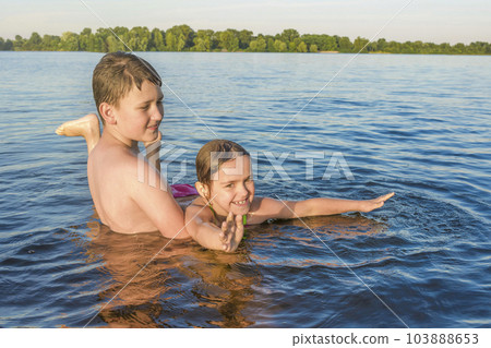 Boy and girl are playing in the water on a sunny day. Happy childhood 103888653