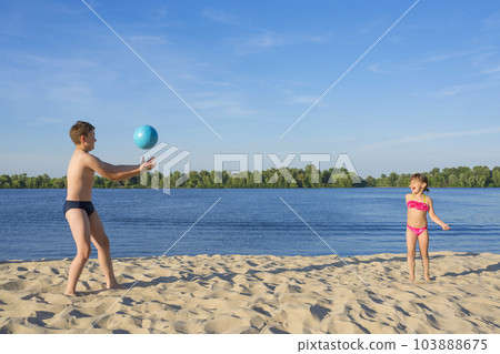 Happy children on the beach play with a ball. Summer holidays. Lifestyle Happy children on the beach play with a ball. Summer holidays. Lifestyle 103888675