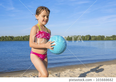 Little girl with a ball in her hands on the river, on a sunny day Little girl with a ball in her hands on the river, on a sunny day 103888682