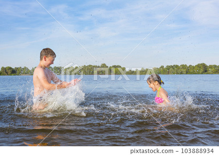 Happy kids play with splashes of water on a sunny day. Happy childhood 103888934