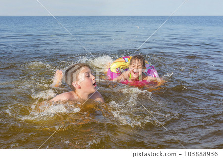 Happy children play in the water on a sunny day. Happy childhood Happy children play in the water on a sunny day. Happy childhood 103888936