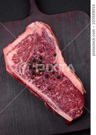 Fresh juicy raw new york beef steak with salt, spices and herbs Fresh juicy raw new york beef steak with salt, spices and herbs 103889058