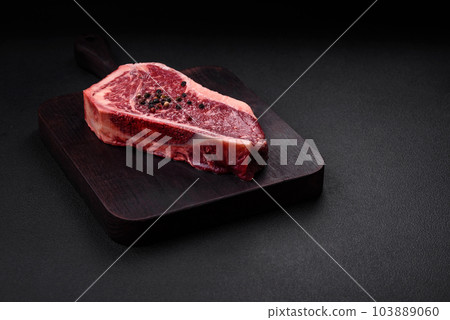 Fresh juicy raw new york beef steak with salt, spices and herbs Fresh juicy raw new york beef steak with salt, spices and herbs 103889060