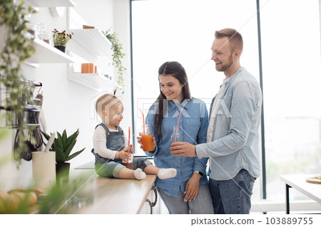 Adorable family of three toasting fresh drinks at home 103889755