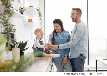 Adorable family of three toasting fresh drinks at home 103889756