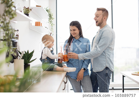 Adorable family of three toasting fresh drinks at home 103889757