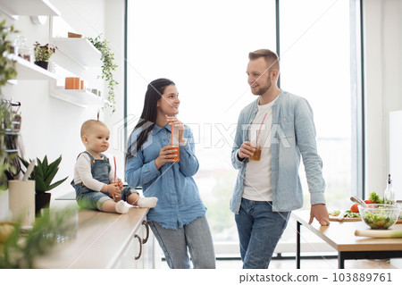 Family consuming tasty vitamin juices in kitchen at home Family consuming tasty vitamin juices in kitchen at home 103889761