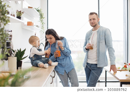 Adorable family enjoying healthy drinks after breakfast Adorable family enjoying healthy drinks after breakfast 103889762