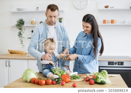 Mom with child pouring olive oil into bowl with dad's help 103889814