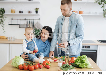 Baby girl posing with parents on kitchen table in apartment 103889908