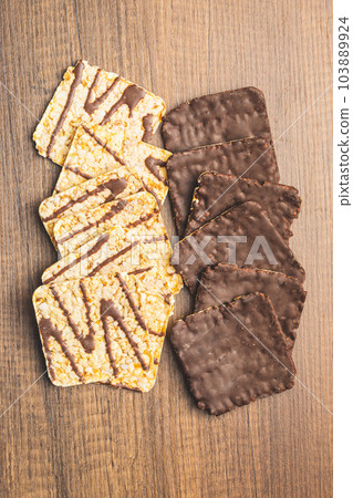 Puffed corn crackers chocolate covered on wooden table. Puffed corn crackers chocolate covered on wooden table. 103889924