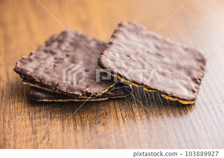Puffed corn crackers chocolate covered on wooden table. Puffed corn crackers chocolate covered on wooden table. 103889927