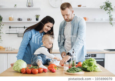 Daughter watching dad making tomato slices on dining table