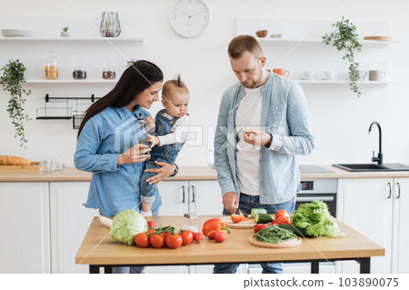 Family of three making homemade meal for dinner together 103890075