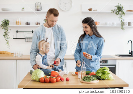 Smiling family preparing meal together in kitchen interior 103890150