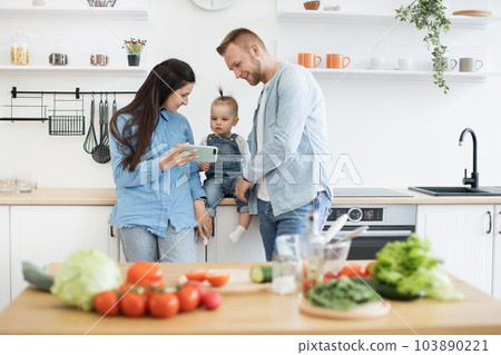 Family searching for recipe of salad on phone in kitchen Family searching for recipe of salad on phone in kitchen 103890221