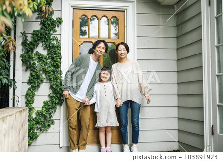 Family portrait standing at the front door of the house 103891923