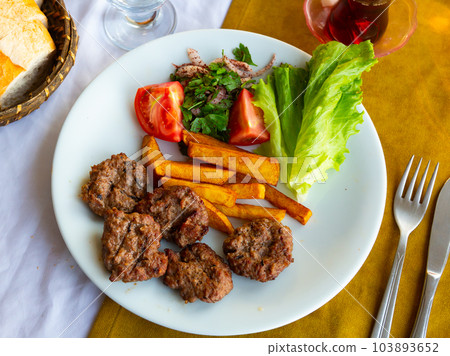 Portion of just cooked inegol kofte with vegetables Portion of just cooked inegol kofte with vegetables 103893652