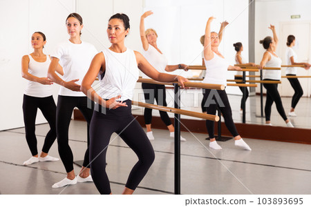 Asian woman rehearsing ballet dance in studio with other dancers 103893695