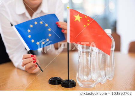Unrecognizable girl sets midget flags of China and European Union before international negotiations 103893762