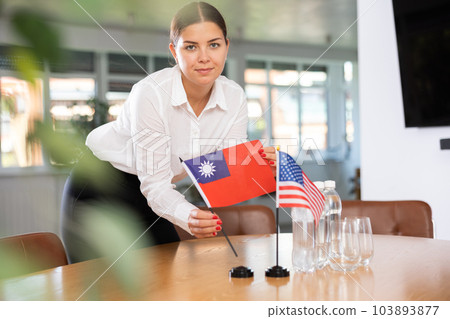 Female office coordinator placing flags of Taiwan and United States on table 103893877