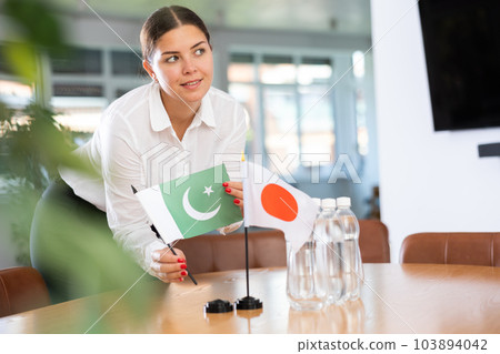 Female coordinator preparing office for Japanese-Pakistani international meeting 103894042