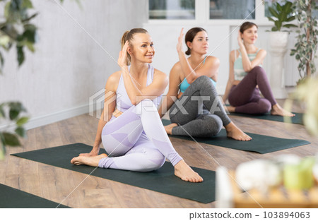 Young focused women doing sage pose in yoga studio 103894063