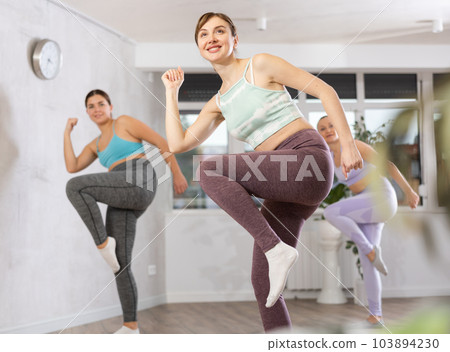 Happy woman training vigorous zumba in fitness studio Happy woman training vigorous zumba in fitness studio 103894230