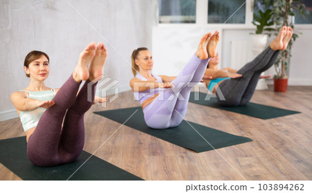 Happy women exercising yoga poses in fitness modern center Happy women exercising yoga poses in fitness modern center 103894262
