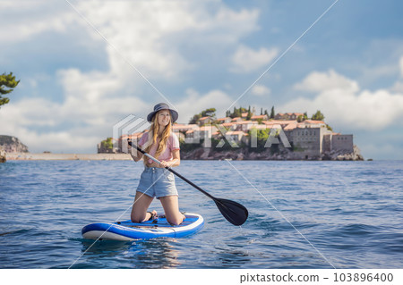 Young women Having Fun Stand Up Paddling in blue water sea near st stefan island in Montenegro. SUP 103896400