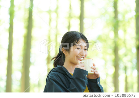 Woman drinking coffee in nature Woman drinking coffee in nature 103896572