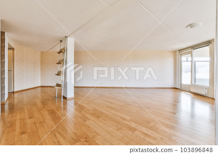 an empty living room with wood flooring and white wallpapers on the walls, in a large open space an empty living room with wood flooring and white wallpapers on the walls, in a large open space 103896848