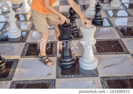 Father and son playing chess spending time together outdoor. Kid play chess 103896931