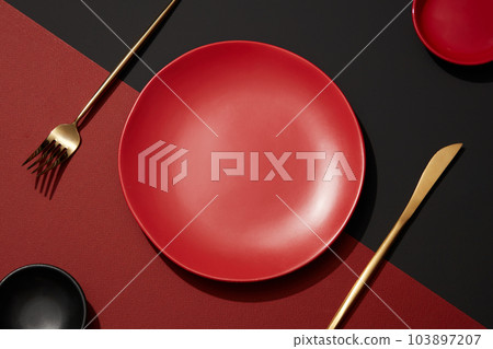 Abstract food background with eating utensil. Top view of an empty round red plates and cutlery decorated on red and background. Setting table for dinner with minimal concept Abstract food background with eating utensil. Top view of an empty round red plates and cutlery decorated on red and background. Setting table for dinner with minimal concept 103897207