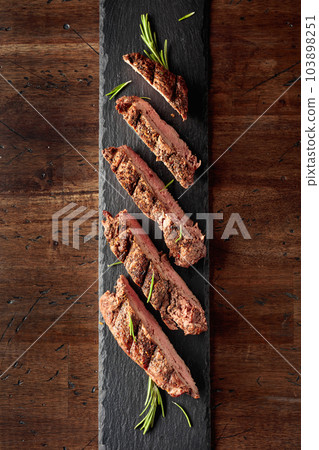 Grilled beef steak on a fork sprinkled with rosemary. 103898251