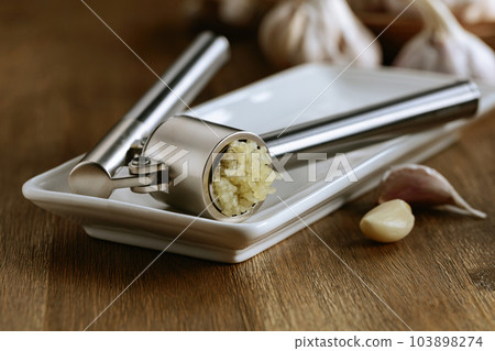 Garlic bulbs and garlic press on a wooden table. Garlic bulbs and garlic press on a wooden table. 103898274