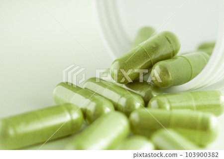 Herbal medicine capsules with bottle on white background 103900382