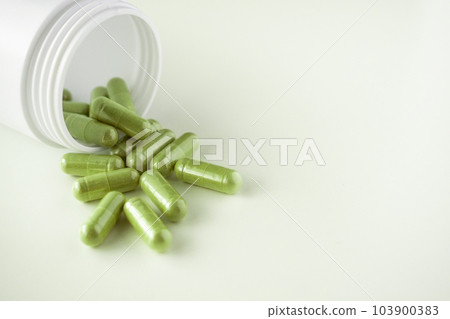 Herbal medicine capsules with bottle on white background 103900383