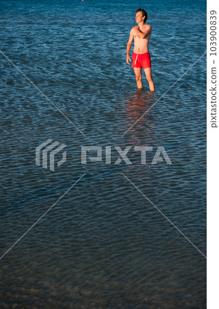 Slim guy posing in red swimwear in sea water 103900839