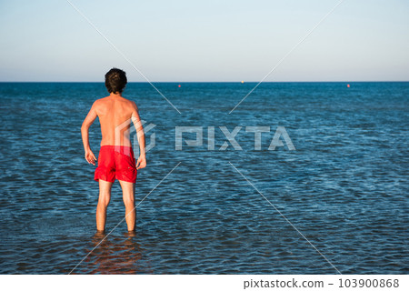 Slim guy posing in red swimwear in sea water 103900868