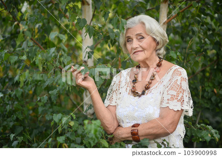 Portrait of happy senior woman smiling in autumn park 103900998