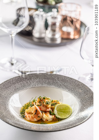 Grilled shrimps on a melted butter with garlic, herbs and chilli with a slice of lime 103901189