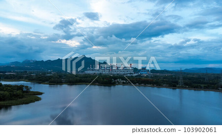 Coal-fired power plant with lake on green mountain background and blue sky. Mae Moh coal power plant in Lampang, Thailand. 103902061